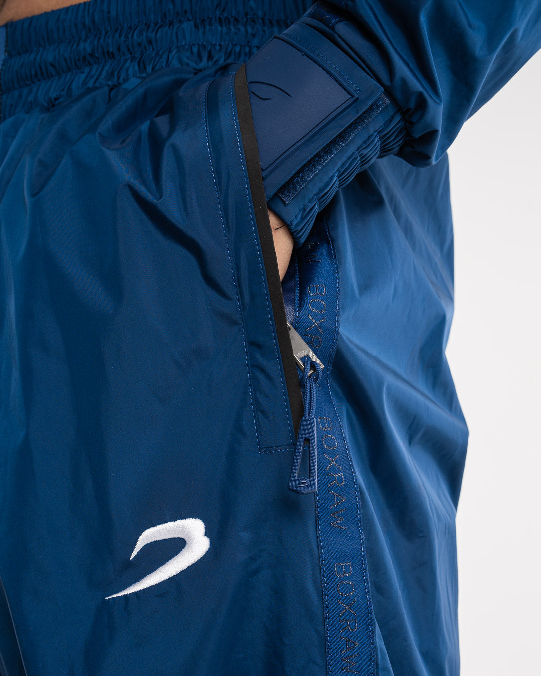 Man in a navy sauna suit tracksuit with a white boxraw logo on the chest as well as adjustable wrist straps and made from polyester.
