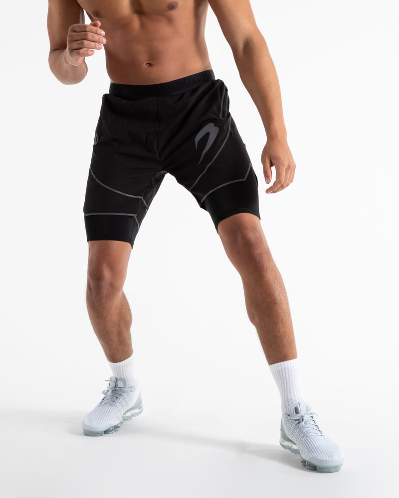 Man in black shorts with compression shorts underlayer with reflective detailing and side zipped pockets